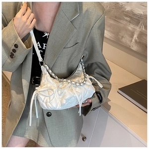 Detail of white quilted cloud bag featuring bow ribbons and silver metal chain strap