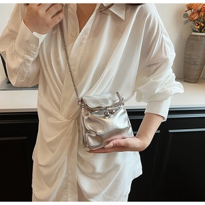 Detail of silver metallic crossbody mini bag with chain strap on a white shirt