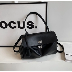 Close-up of black PU leather tote bag featuring a silver twist lock and accordion sides