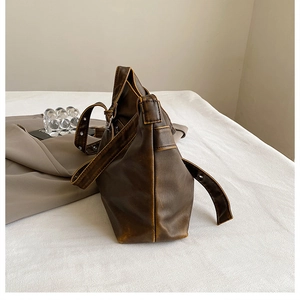 Detail view of deep brown oily wax leather texture and wide adjustable strap on the bag