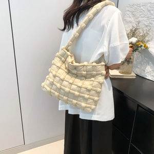 Detail view of cream white shoulder bag featuring thick quilted woven pattern and wide strap