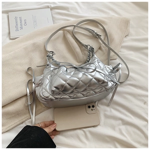 Detail of silver quilted crescent bag with metallic finish and bow ribbon accents