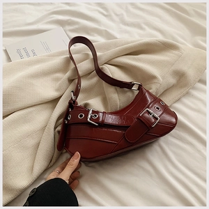 Détail du sac croissant bordeaux avec boucle argentée et accents métalliques à œillets