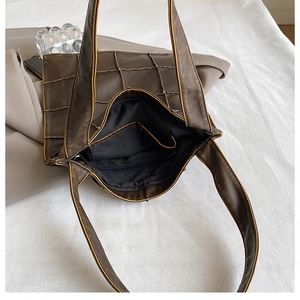 Detail view of large brown tote bag showing zipper opening, inner pocket, and textured lining