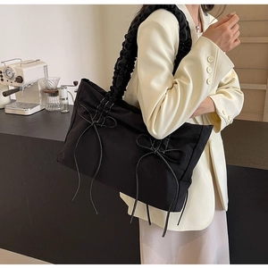 Detail van zwarte shopper met decoratieve strikken en trendy gerimpelde schouderband
