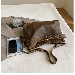 Detail of retro brown leather shoulder bag with vintage buckle and adjustable strap