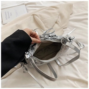 Detailed view of silver quilted crossbody bag with metal chain and interior lining