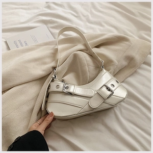 Détail d'un sac sous le bras en cuir beige avec boucles argentées et sangles style vintage
