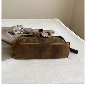 Macro view of vintage brown leather crossbody bag featuring yellow contrast stitching