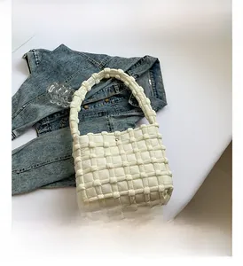 Detail of white woven quilted fabric handbag with puffy texture and thick handle