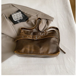 Macro detail of dark brown leather texture and silver buckle on vintage crossbody bag