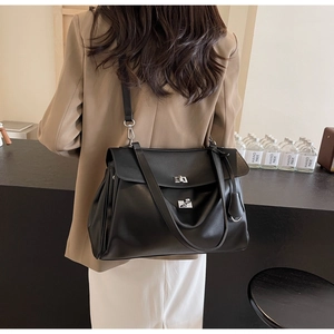 Detail of black matte leather tote bag with silver buckles and pleated accordion sides