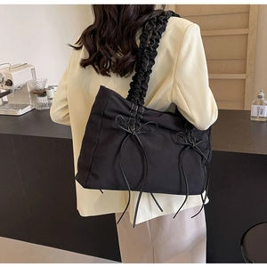 Detail van zwarte geplooide shopper met strikjes gedragen bij een beige blazer in café