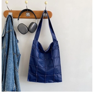 Close-up of quilted navy blue tote bag with unique cross-stitch pattern for daily commute