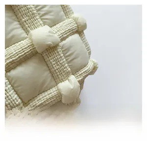 Detailed close-up of cream quilted fabric showing textured puffy grid and high-quality stitching