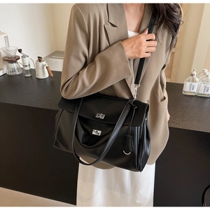 Detail of black leather tote bag featuring a silver twist lock and adjustable shoulder strap