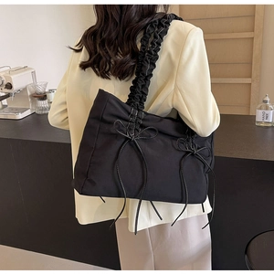 Detail van nylon schoudertas met geplooide handgreep en wit gestikte strikjes