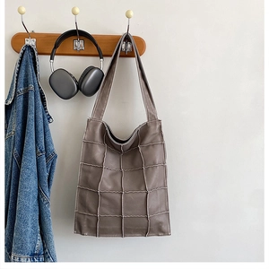 Detail of soft brown faux leather tote with vintage exposed stitching grid texture
