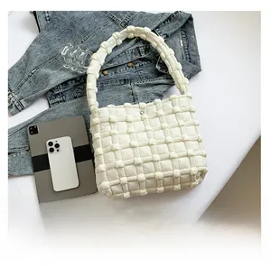 Detailed view of a white quilted puffer tote bag styled with a tablet and mobile phone