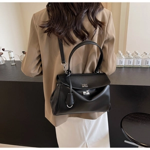 Detail of black leather handbag with silver twist-lock and detachable shoulder strap