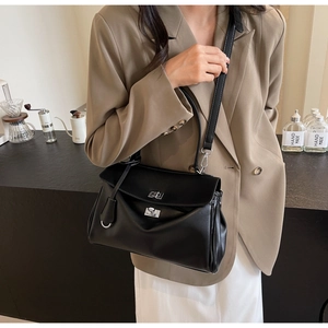 Chic black leather handbag with silver clasp worn by model in a cozy cafe setting