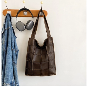Detail view of deep brown quilted leather tote bag with square texture and shoulder strap