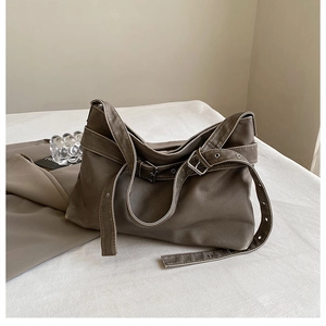 Detail of dark green leather handbag showing texture and silver metal buckle adjustment