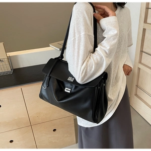 Detailed side view of a large black leather shoulder bag with silver twist lock for commuting