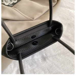 Macro detail of black nylon mini bag showing magnetic buckle and metal D-rings for strap