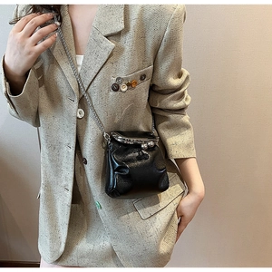 Dettaglio della mini borsa a secchiello nera con chiusura a scatto retrò e catena in metallo
