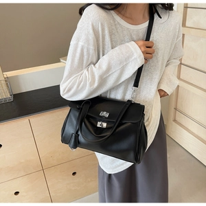 Detailed view of a black leather crossbody bag with a silver metal twist lock closure
