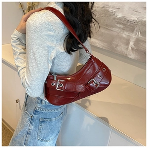Détail du sac sous le bras en cuir verni bordeaux avec boucles en métal et style Y2K