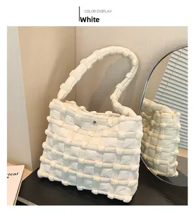 Detailed view of white quilted shoulder bag with woven texture and magnetic metal clasp