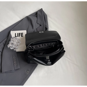 Detail view of black leather handbag interior with multiple compartments and silver hardware