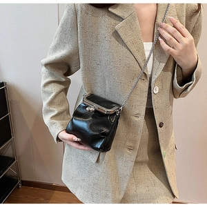 Détail d'un mini sac bandoulière noir texturé avec fermoir en métal argenté et chaîne