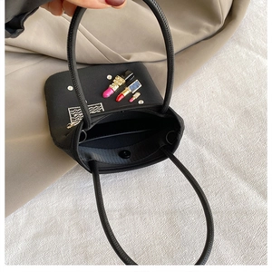 Detail view of small black nylon bag featuring lipstick patches and crystal accents
