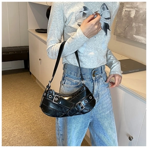 Détail d'un sac sous le bras en cuir noir brillant avec boucles et œillets en argent