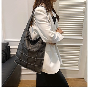 Detail showing high-quality black quilted tote bag with intricate square stitching accents