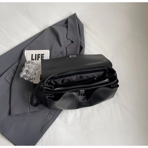 Interior detail of black leather bag showing organized three-layer accordion structure