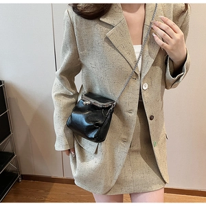 Detail of black frame bag with silver clasp and chain strap on tweed blazer