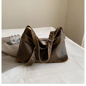 Detail of dark brown leather tote bag showing vintage texture and silver buckle accents