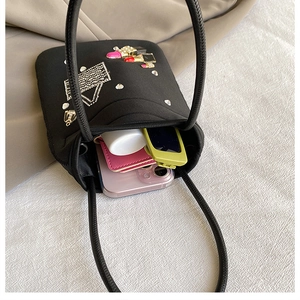 Detail view of the black nylon mini bag capacity showing phone, wallet and sunglasses
