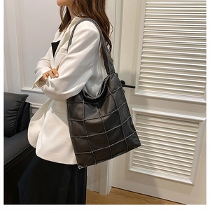Detail of black tote bag showing white contrast stitching and soft leather texture