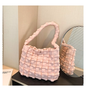 Close-up of pink quilted puff shoulder bag with soft textured fabric and magnetic closure