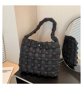 Detailed view of black woven puff shoulder bag with soft quilted texture and metal clasp