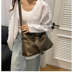 Detail of dark brown leather crossbody bag featuring silver buckle and adjustable strap