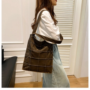 Detailed view of brown large tote bag with quilted pattern and wide shoulder strap