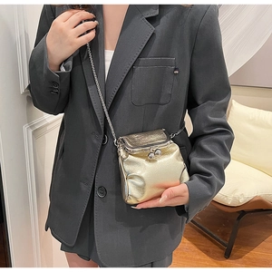 Close-up of golden metallic frame crossbody bag with retro double bead clasp and chain strap