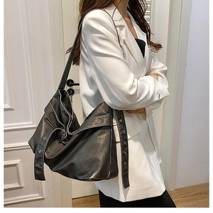 Detail of grey leather tote bag with long shoulder strap and metallic eyelet decor