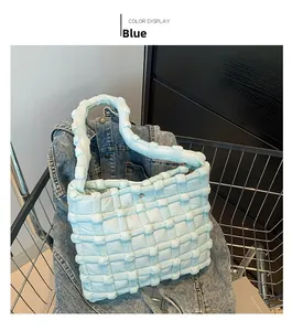 Detailed texture of blue quilted puffer tote bag in a metallic shopping cart
